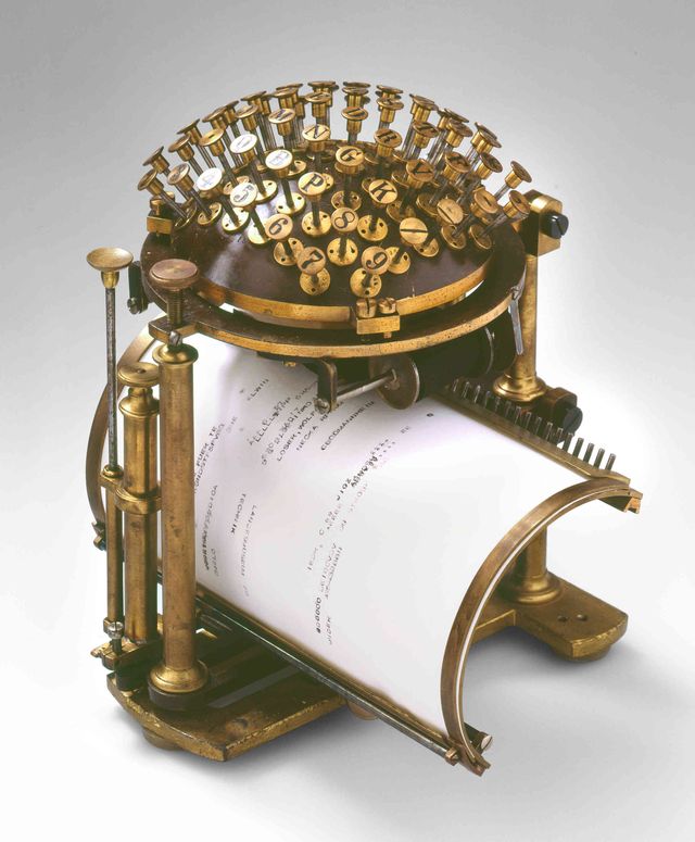 Schreibmaschine in Form einer Halbkugel. Die Tasten befinden sich auf der Kugel, das Papier ist auf eine gebogene Blatte gespannt