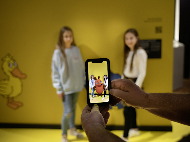 Auf einem Smartphone-Screen sind zwei Kinder zusammen mit der virtuellen Maus aus der Sendung "Die Sendung mit der Maus" zu sehen.