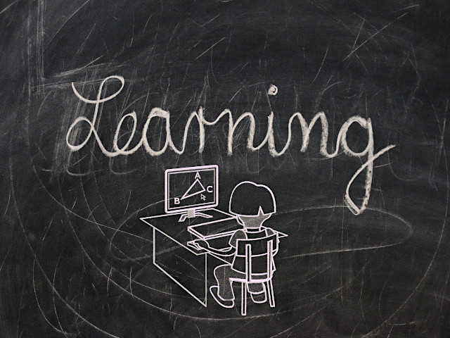 Eine Tafel, auf der in Schreibschrift das Wort Learning zu lesen ist. Darunter ein Kind vor einem Notebook.