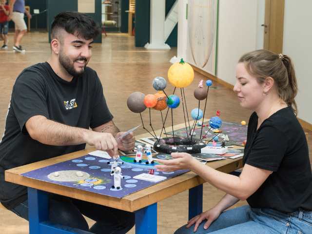 Ein Mann und eine Frau betrachten ein Modell der Planeten unseres Sternensystems